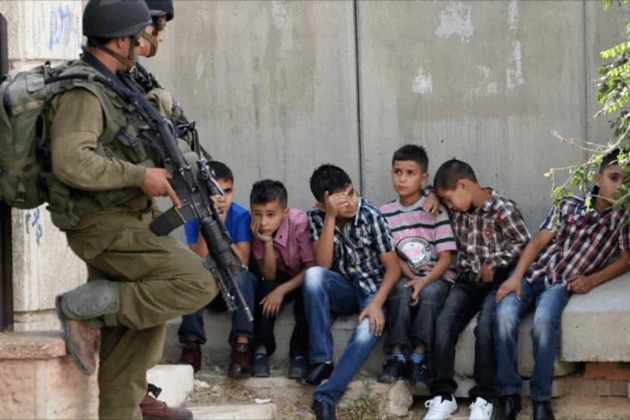 Israeli soldiers stand guard over Palestinian children arrested in the West Bank city of Hebron