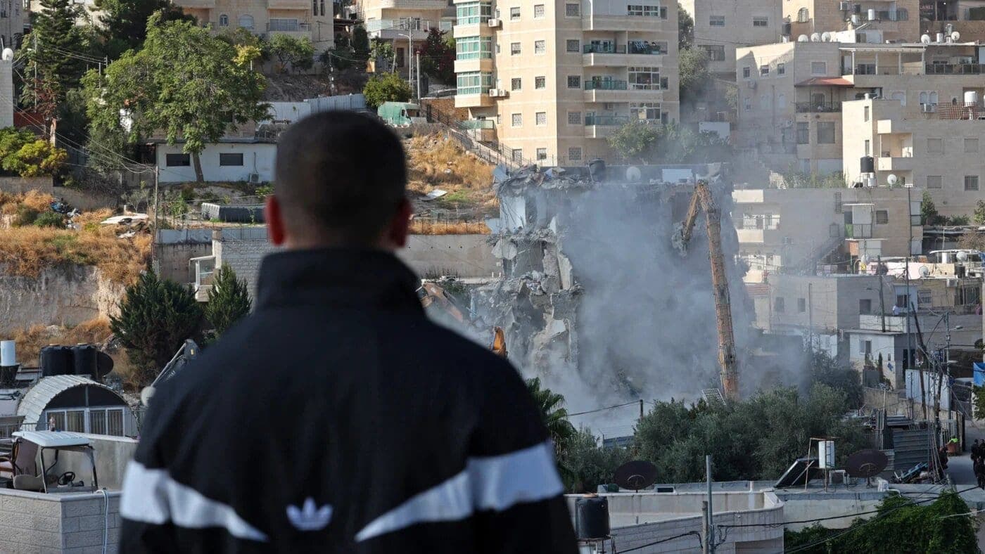 A man watches Israeli forces demolish a Palestinian-owned residential building in occupied East Jerusalem on 6 October 2026 (Ahmad GHARABLI/AFP)