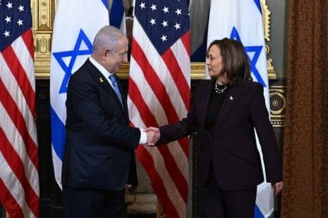 a man and woman shaking hands, american and israeli flags beside them